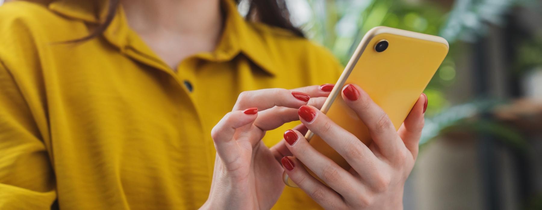 a woman holding a yellow cell phone